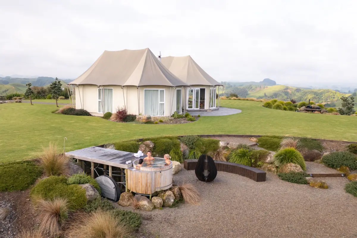 Pōhutukawa Tent dining room with open bifold doors and countryside views, NZ