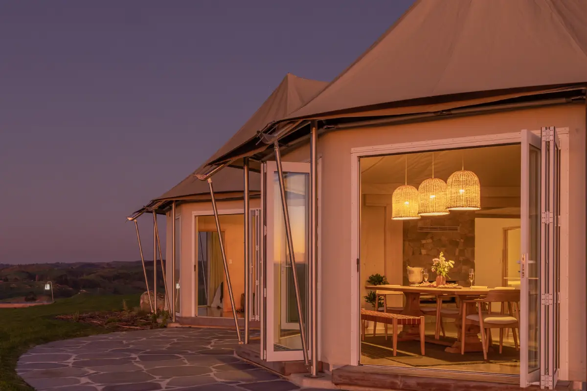 Pōhutukawa Tent exterior at dusk with folding doors open, Wild Canvas Waitomo