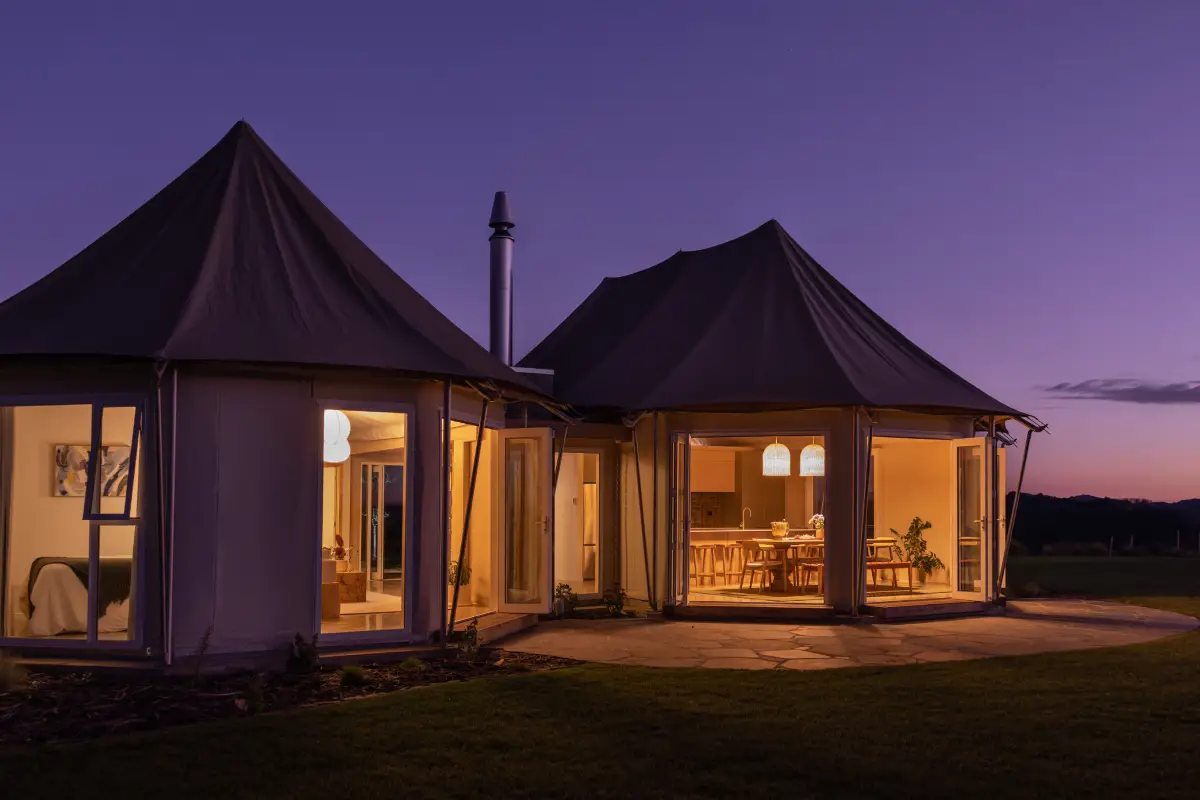 Pōhutukawa Tent exterior with lawn and guests enjoying panoramic views, glamping NZ