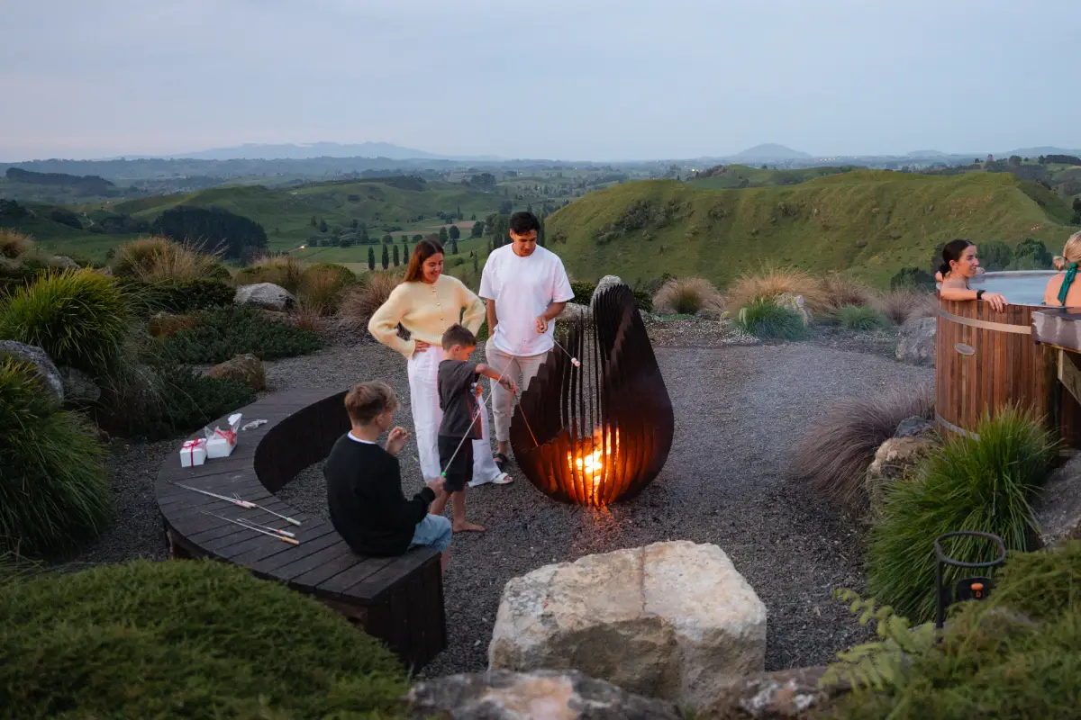 Pōhutukawa Tent fire pit with family toasting marshmallows, glamping Waitomo