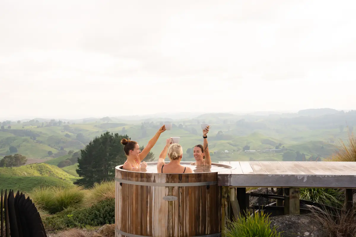 Friends in cedar hot tub with morning coffee, Pōhutukawa Tent Waitomo