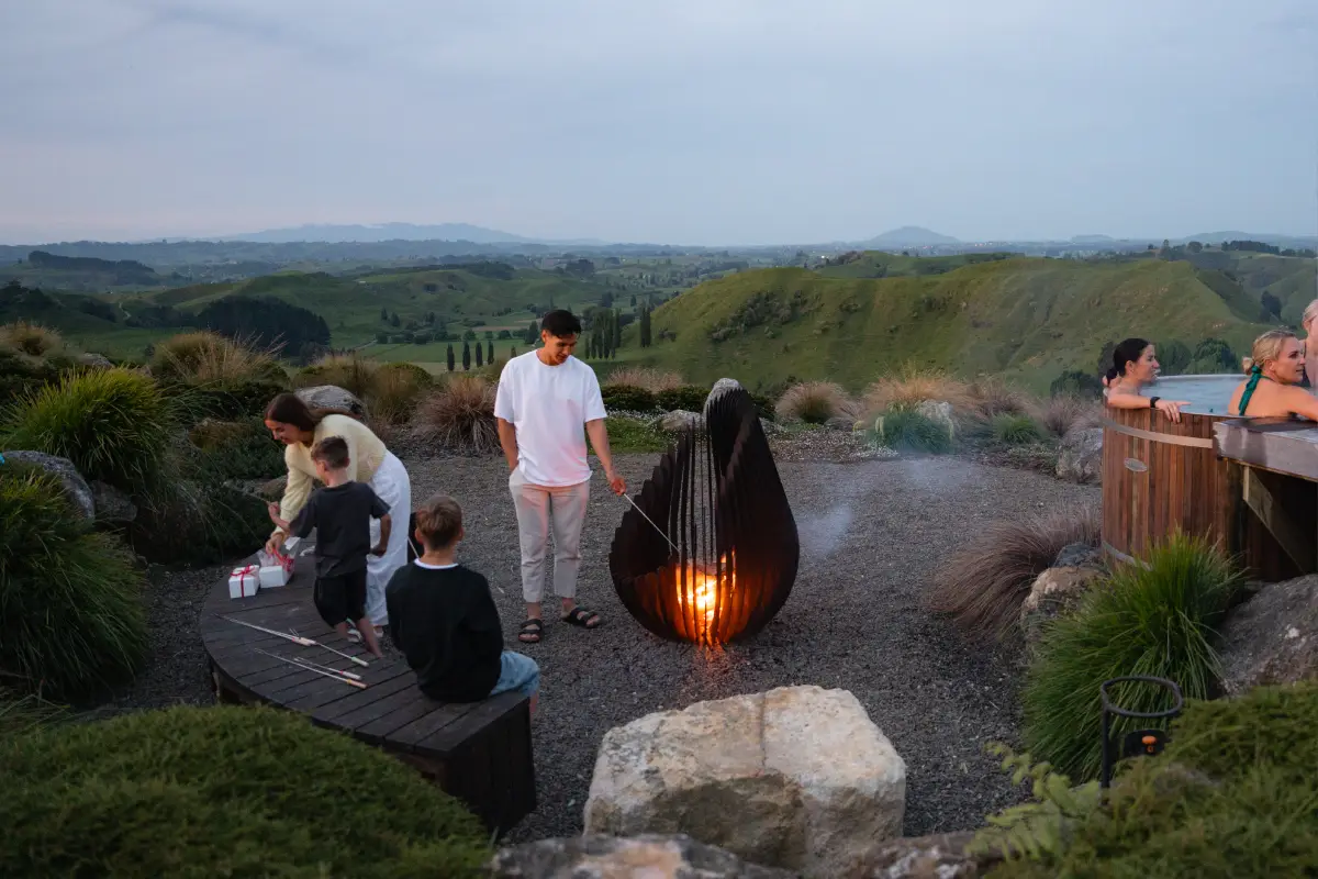 Family toasting marshmallows around the firepit at Pōhutukawa Tent, Waitomo