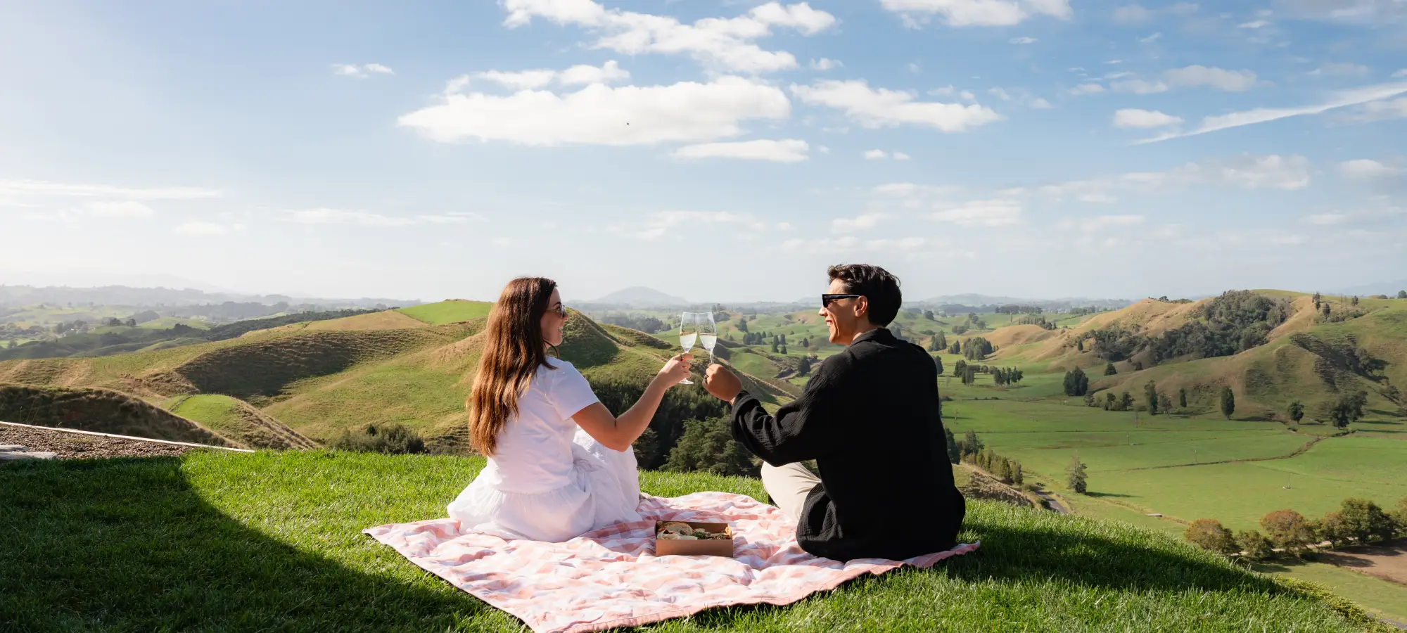Couple enjoying champagne on the hilltop at Wild Canvas Waitomo